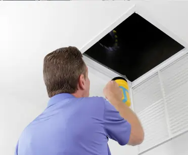 Air duct cleaning technician removing ceiling vent